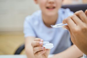 Ophthalmologist showing contact lenses to child in clinic